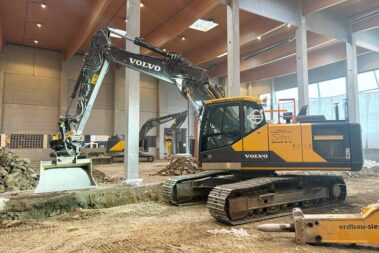 Bagger beim Einsanden einer Baugrube