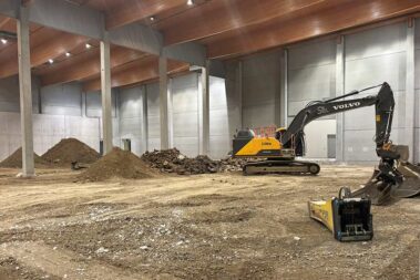 Ein Bagger in der Halle, dahinter Erd- und Bauschutthaufen.